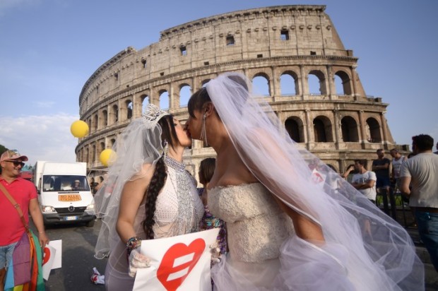 Brides kiss near the Colosseum during the Gay Pride Parade (LGBT) on June 13, 2015 in Rome.  AFP PHOTO / FILIPPO MONTEFORTE        (Photo credit should read FILIPPO MONTEFORTE/AFP/Getty Images)